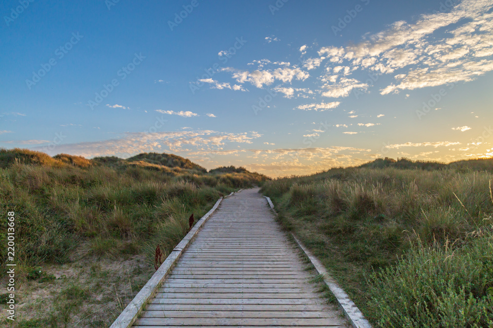 A wooden pathway leading towards the sea at Formby in Merseyside, taken at sunset