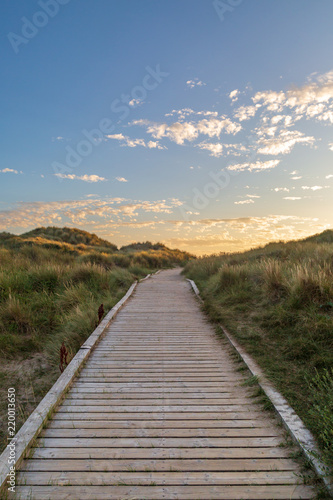 Fototapeta Naklejka Na Ścianę i Meble -  A wooden pathway leading towards the sea at Formby in Merseyside, taken at sunset