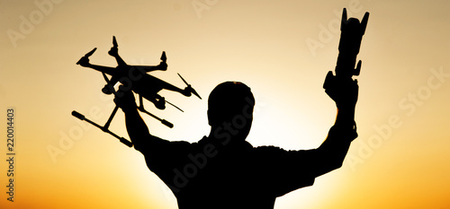 a man holds a drone and a camera at sunset
