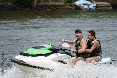 Happy young couple enjoying and having fun riding on a jet ski. Tropical coast of Sri Lanka