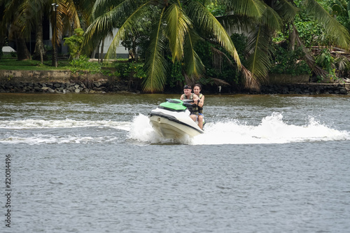 Happy young couple enjoying and having fun riding on a jet ski. Tropical coast of Sri Lanka