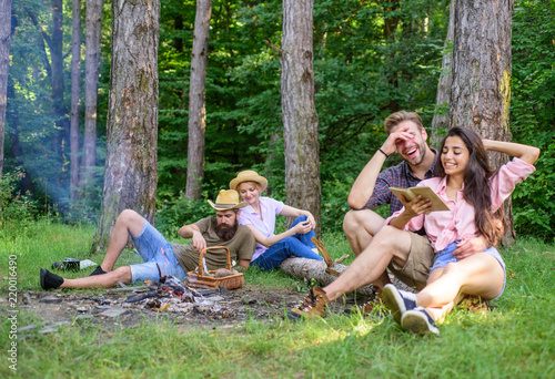 Couples or families having great time relaxing near campfire. Couples spend time outdoors on sunny day. Youth on picnic or hike relaxing and having fun. Couples tourists rest forest. Pleasant weekend