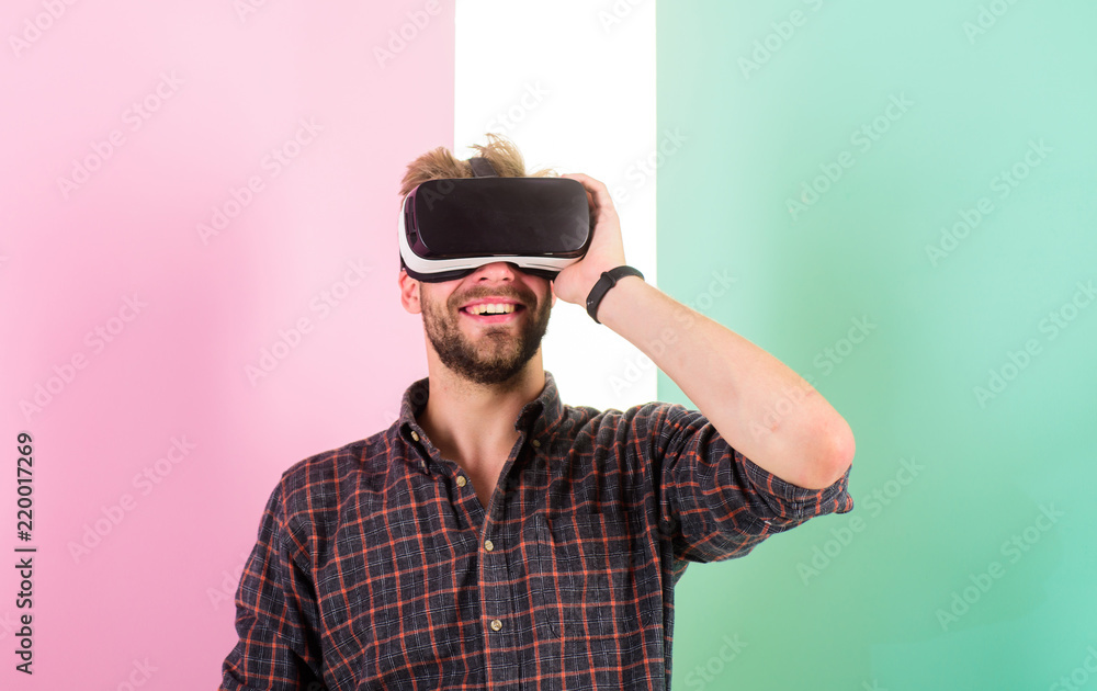 Man unshaven guy with VR glasses involved in cyber space, pink background. Hipster use modern technologies for entertainment. Cyber space. Guy VR glasses head mounted display interact in cyber space