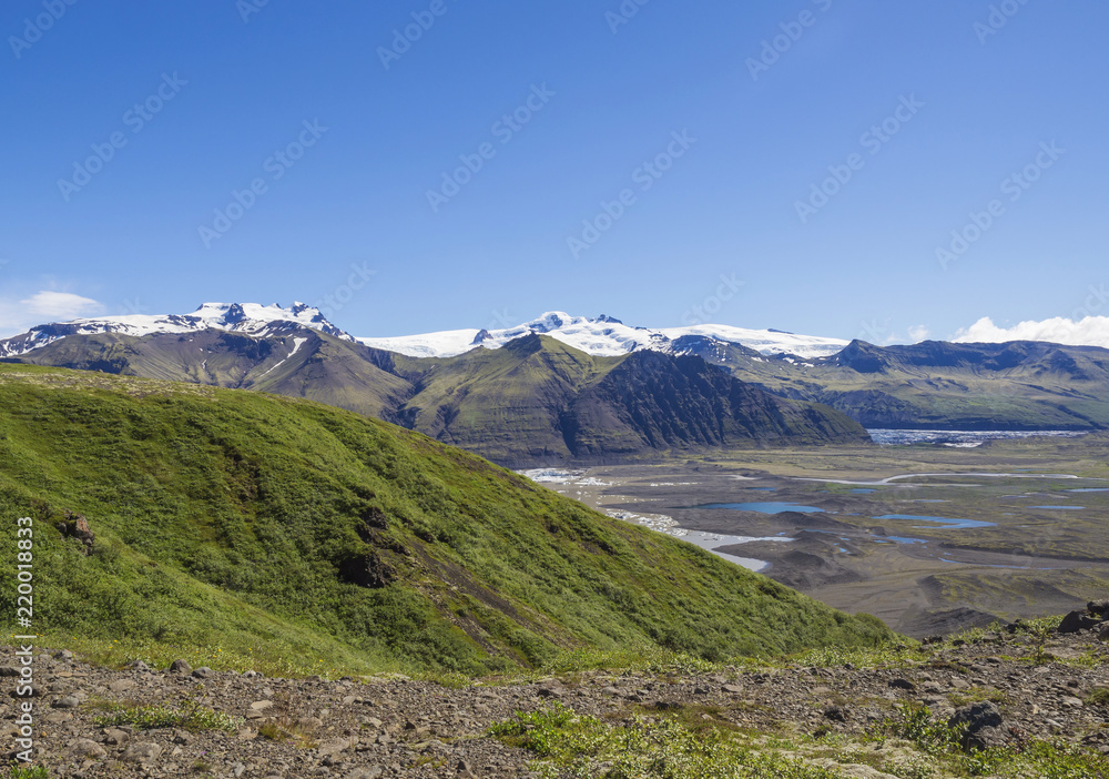 View on glacier lagoon with icebergs and tongue of Skaftafellsjokull, colorful rhyolit mountains in Skaftafell