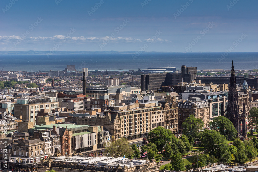 Edinburgh, Scotland, UK - June 14, 2012: Wide view from top of castle towards North Sea inlet and Princess street with Scott Monument, under blue sky.