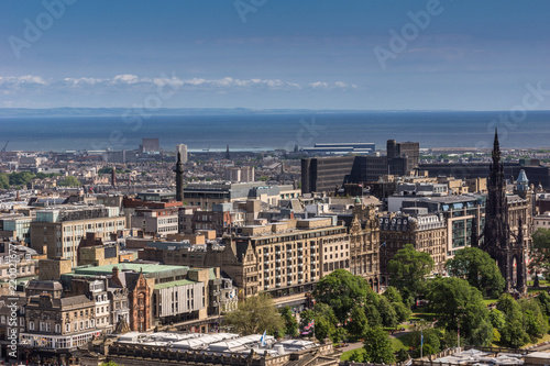 Edinburgh, Scotland, UK - June 14, 2012: Wide view from top of castle towards North Sea inlet and Princess street with Scott Monument, under blue sky.