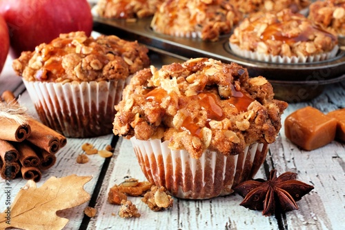 Autumn caramel apple muffins. Close up table scene on a white wood background.