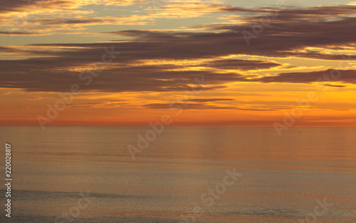 Golden sunset colors of orange  gold  blue clouds reflected in calm ocean
