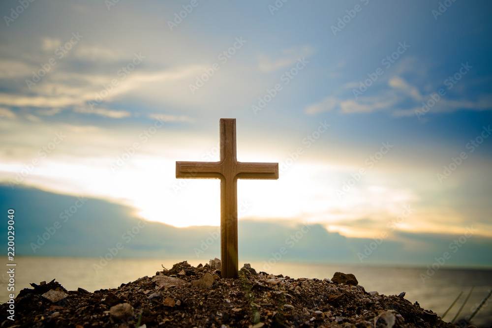 The cross standing on meadow sunset and flare background. Cross on a hill as the morning sun comes up for the day.The cross symbol for Jesus christ.Christianity, religious, faith, Jesus or belief.