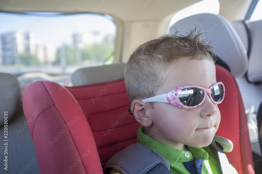 Handsome child boy wearing sunglasses inside the car Handsome child boy wearing sunglasses inside the car