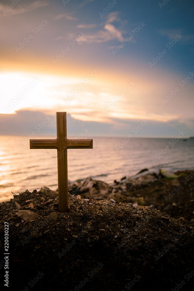 The cross standing on meadow sunset and flare background. Cross on a hill as the morning sun comes up for the day.The cross symbol for Jesus christ.Christianity, religious, faith, Jesus or belief.