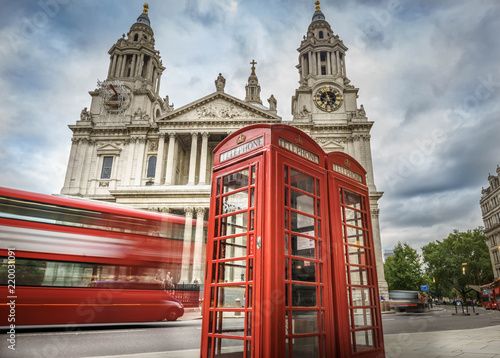 red phone boxes and red bus passing Saint Paul's Cathedral in London at cloudy day