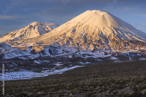 The great "Nevados de Payachatas" with the Pomerape and Parinacota Volcanoes, left and right respectively over the Atacama desert meadows during sunset an amazing colorful landscape, Arica, Chile © abriendomundo