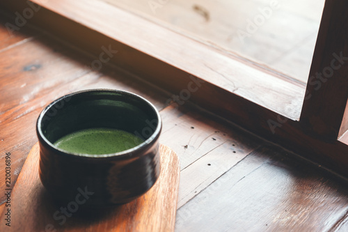 A cup of hot matcha latte on wooden floor