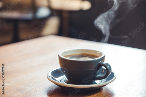 Closeup image of a blue cups of hot coffee with smoke on vintage wooden table in cafe