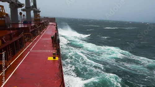 Cargo ship rolling in stormy sea. Huge waves under blue sky in Indian Ocean