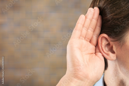 Businessman holds his hand near his ear and listening something