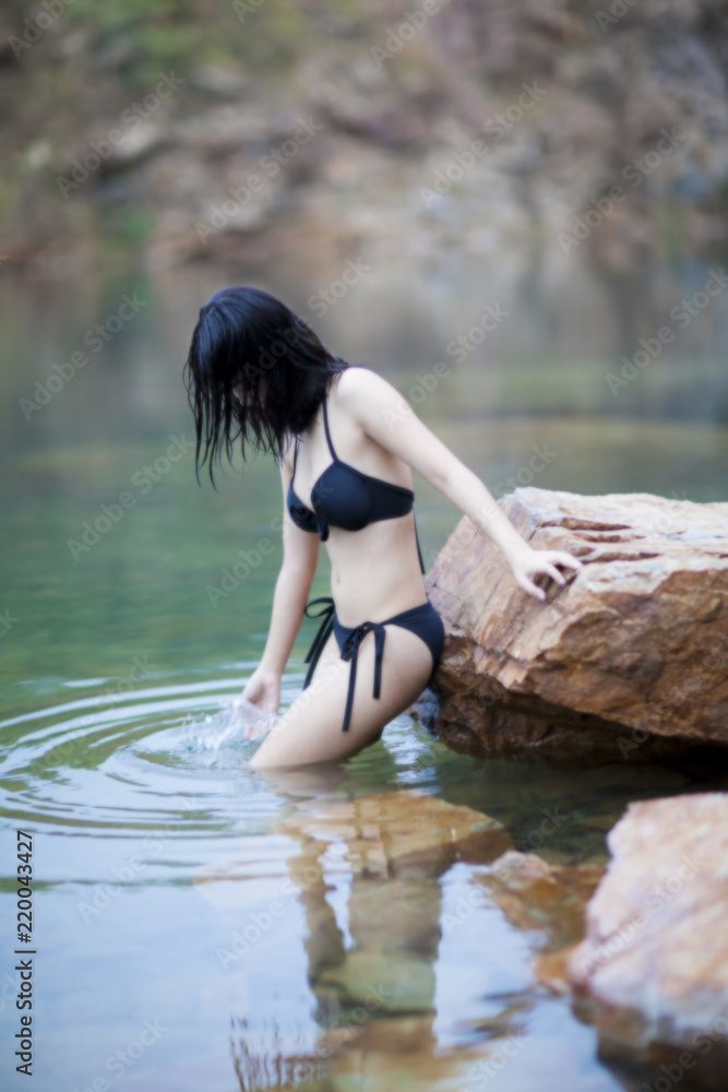 Elegant sexy woman in the black bikini and shapely body is posing in the lake. soft and blur style for background. Portrait of sexy woman in black bra on underwear standing in lake Elegant sexy woman in the black bikini and shapely body is posing in the lake. soft and blur style for background. Portrait of sexy woman in black bra on underwear standing in lake