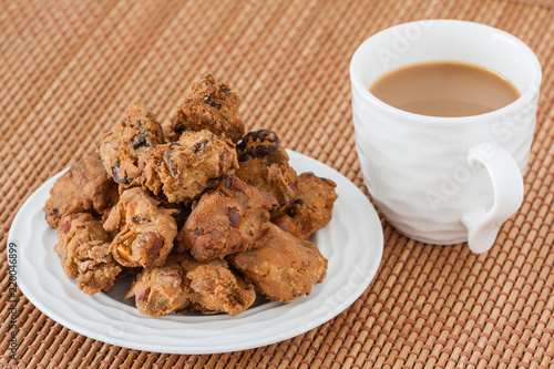 Indian pakoda snack with coffee - A macro closeup of traditional deep fried Indian snack pakkoda on a plate served with coffee. A variety of nuts and flour is used to prepare it. photo