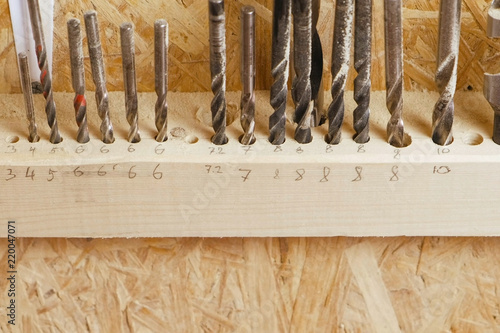 Drills of different sizes in the workshop. Set of drill bits stand in a row.