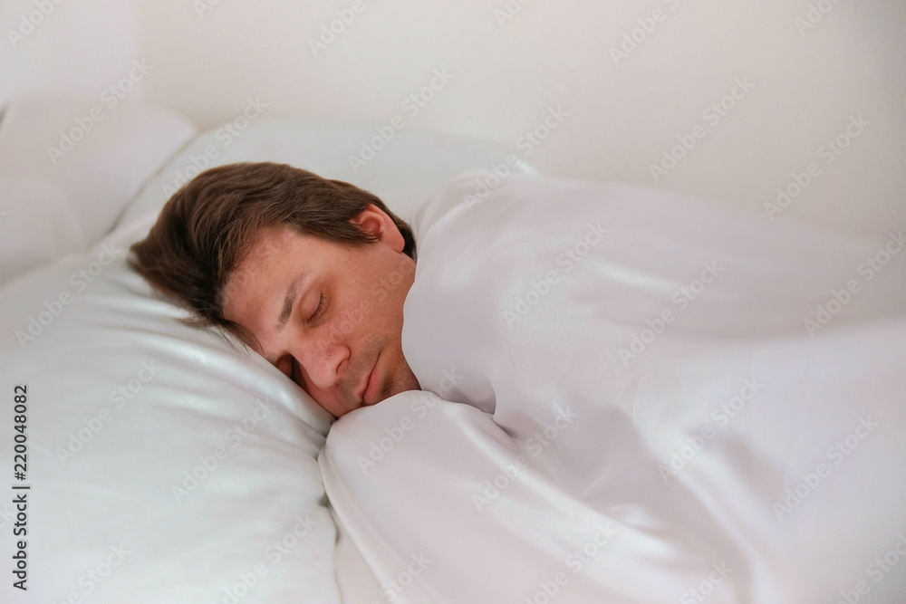 Man is sleeping in bed alone under the blanket. Side view. Man is sleeping in bed alone under the blanket. Side view.