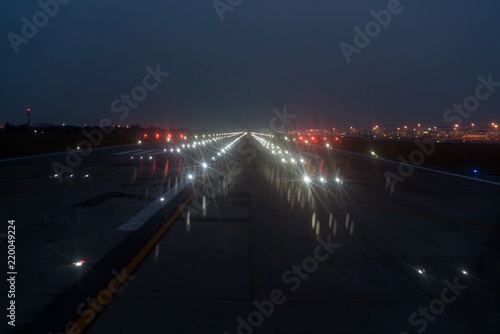 Landing lights ON A airport runway at night time.