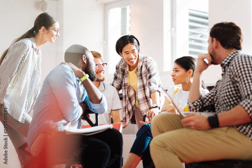 Educational process. Positive emotional young people sitting in a little circle and smiling while having an interesting discussion at the university Educational process. Positive emotional young people sitting in a little circle and smiling while having an interesting discussion at the university