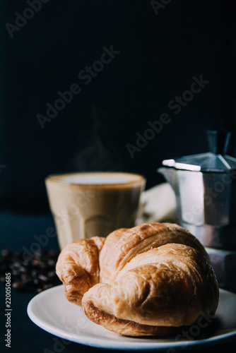 Fototapeta Naklejka Na Ścianę i Meble -  Croissant ,Latte art ,and moka pot with Roasted coffee on black background in the morning and instagram style filter photo vintage tone