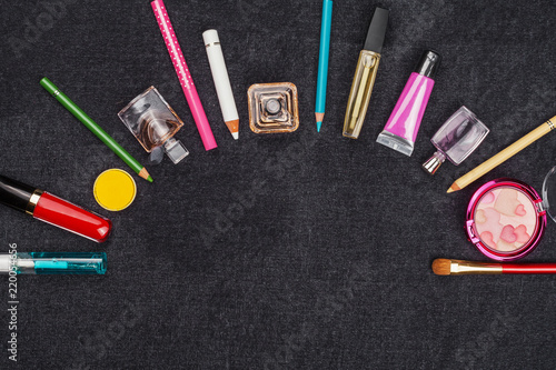 composition of various decorative cosmetics including lipstick eye pencil, powder mascara and perfumes. concept of professional makeup. black background and free space for text