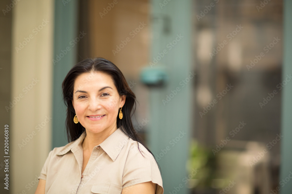 Happy Hispnaic woman smiling and standing outside.