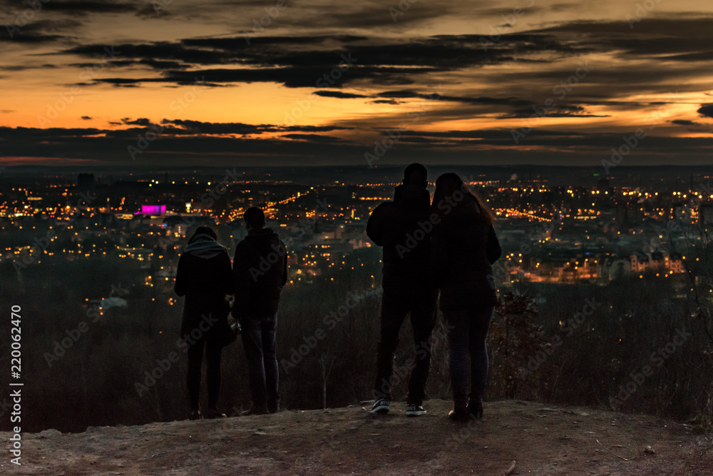 couples lookin at a city from a mountain peak