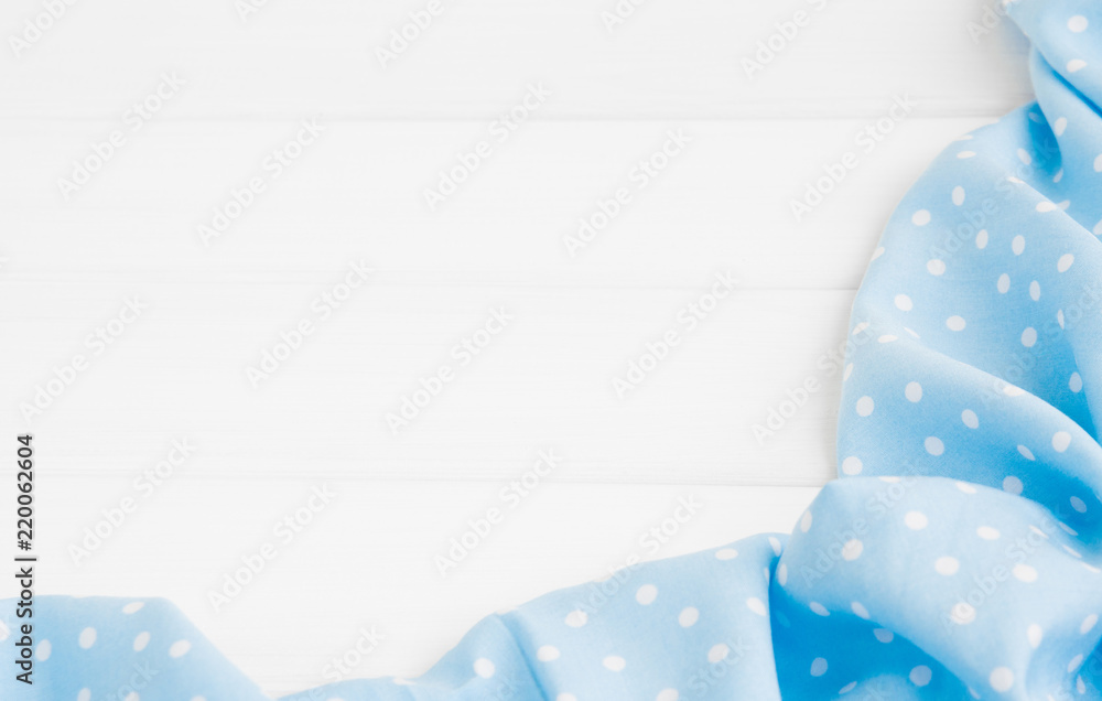Obraz premium Light blue polka dots folded tablecloth over bleached wooden table. Top view image. Copyspace for your text.