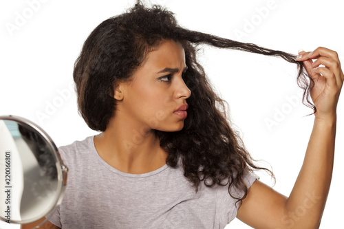 portrait of young dark-skinned woman with hair splitting problem on white background