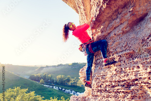 Photo of woman in sunglasses clambering over rock up