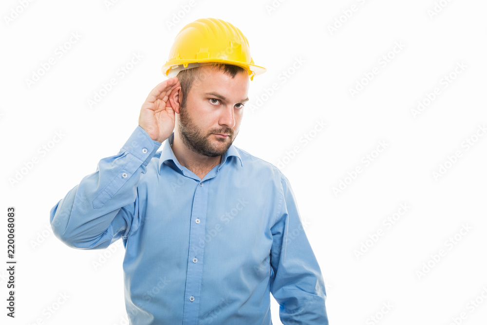 Young architect with yellow helmet showing can't hear gesture
