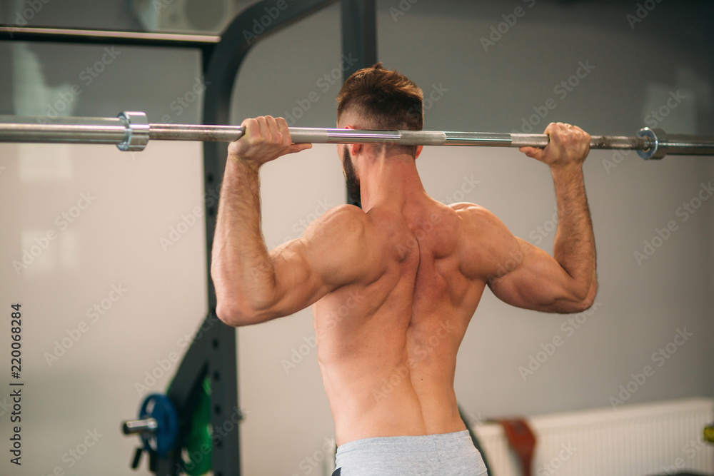 A young athlete trains in the gym. Shows the muscles of the back and chest