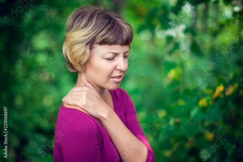 Woman put her hand on the back of her neck while feeling pain. Healthcare, medicine and people concept