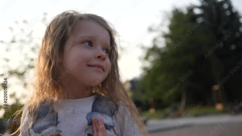 Cute child girl portrait coquettishly plays with hair jumping on playground trampoline Cute child girl portrait coquettishly plays with hair jumping on playground trampoline