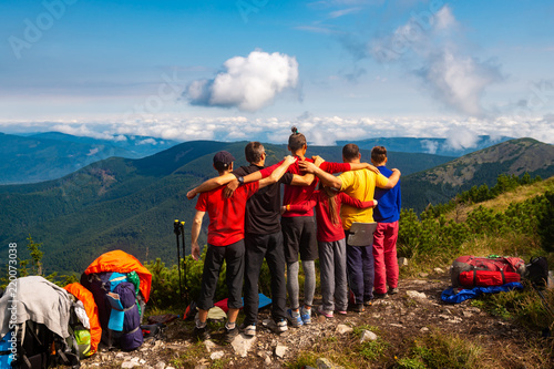 Obraz na płótnie Hikers, friends stand, embracing on a mountain top w salonie