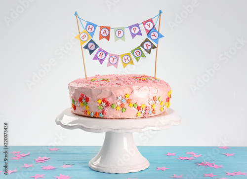 Stand with tasty birthday cake on table