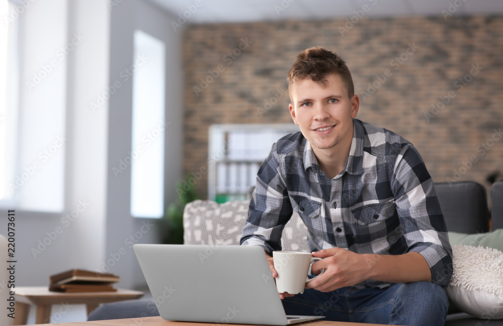 Handsome young man working on laptop at home Handsome young man working on laptop at home