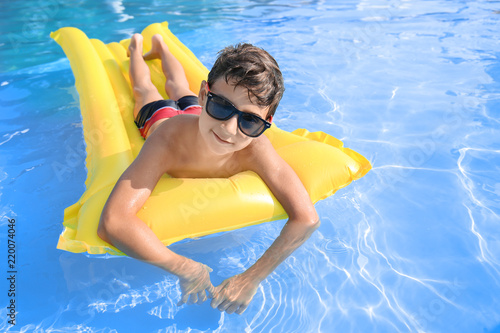 Cute little boy resting on inflatable mattress in swimming pool