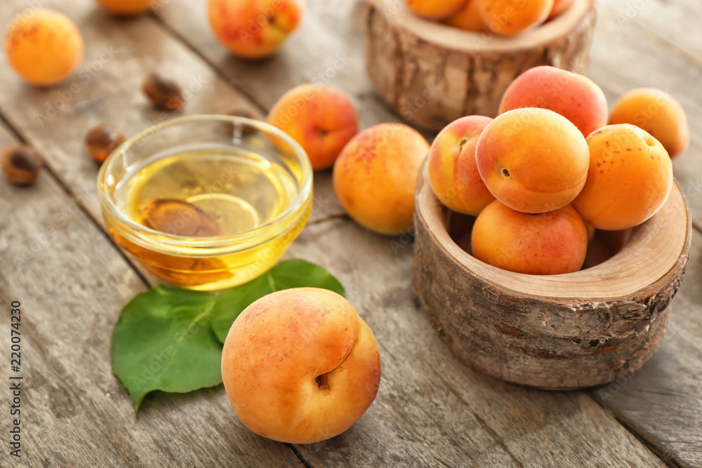 Bowl with essential oil and fresh apricots on wooden table Bowl with essential oil and fresh apricots on wooden table