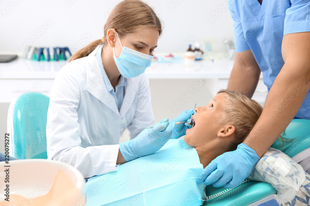 Fototapeta premium Dentist examining little boy's teeth in clinic