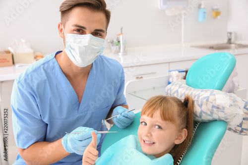 Cute little girl showing thumb-up gesture at dentist s office