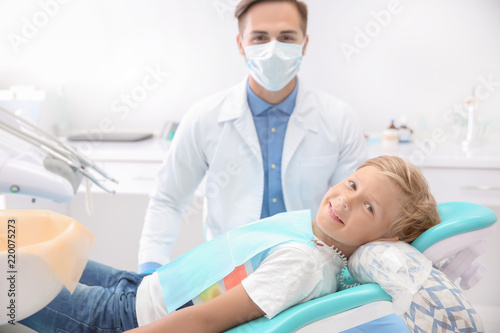 Dentist examining little boy's teeth in clinic