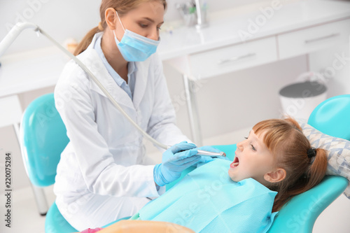 Dentist filling little girl's teeth in clinic