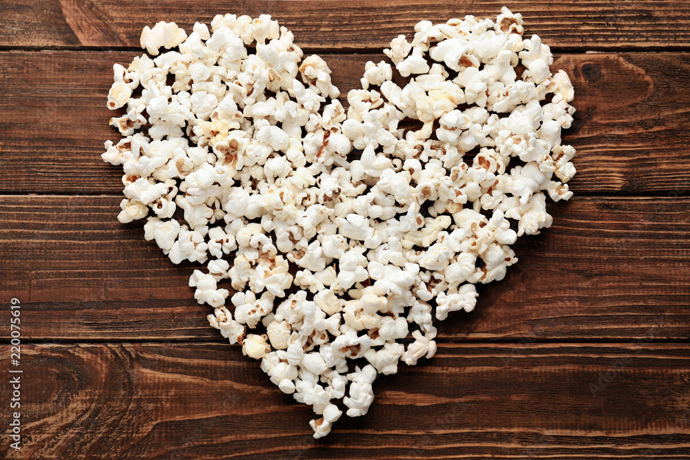 Heart made of delicious popcorn on wooden table
