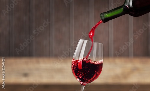 Red wine pouring in glass isolated on white background