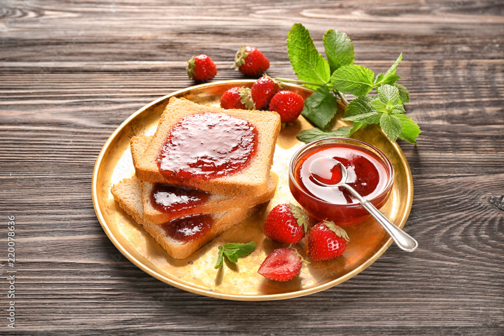 Plate with slices of bread and delicious strawberry jam on wooden table Plate with slices of bread and delicious strawberry jam on wooden table